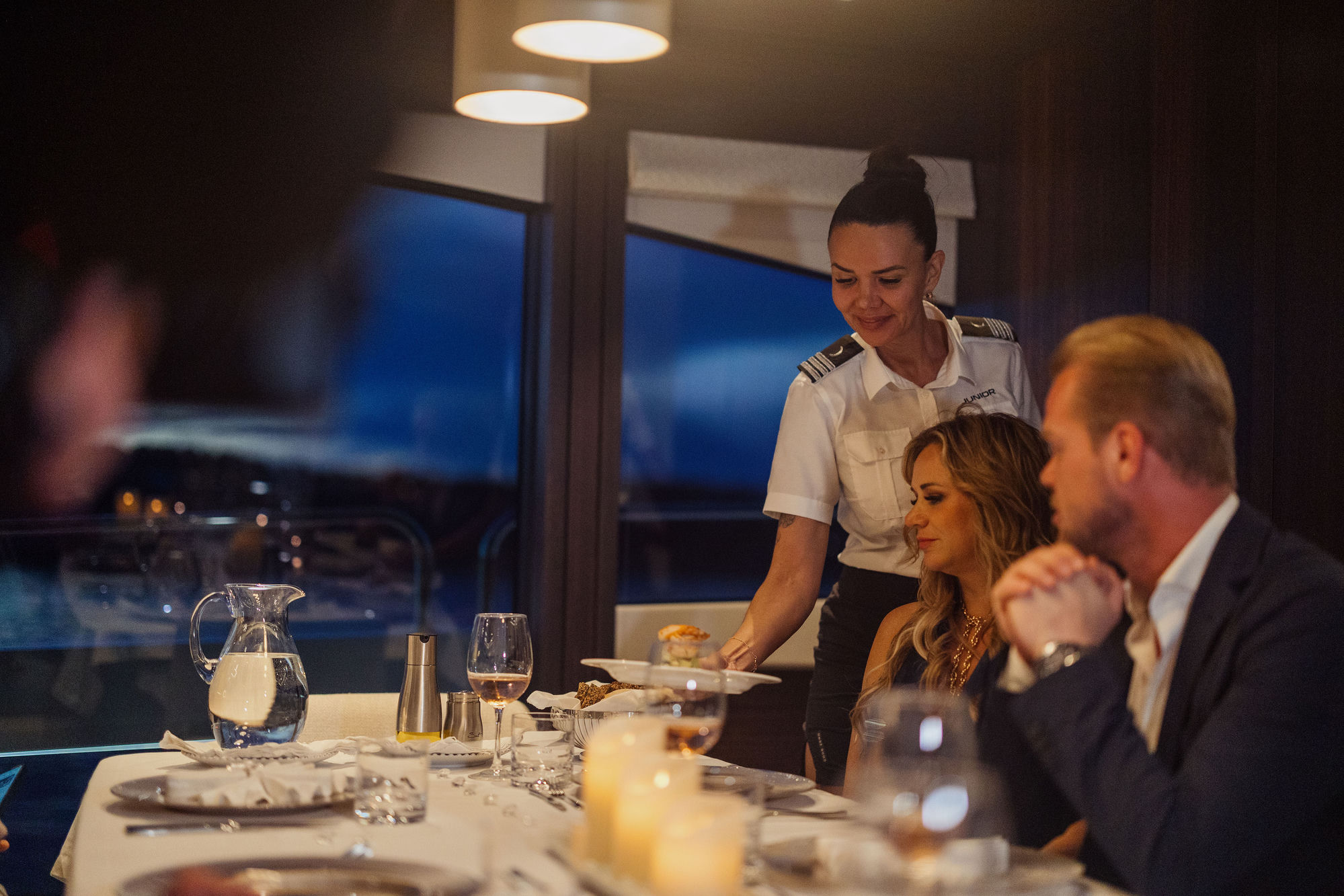 Stewardess providing attentive service aboard M/Y Lio Black Knight Sunseeker 95 — luxury charter crew